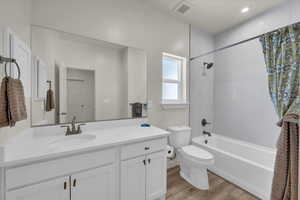 Full bathroom featuring vanity, toilet, shower / bath combo with shower curtain, and wood finished floors