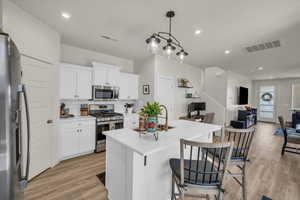 Kitchen featuring appliances with stainless steel finishes, light wood-style flooring, open floor plan, backsplash, and light countertops