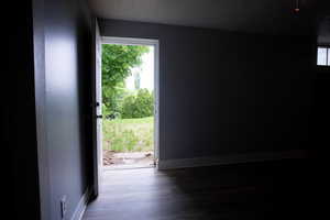 Doorway with wood finished floors and baseboards