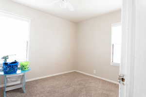 Carpeted empty room featuring a ceiling fan and baseboards