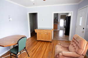 Living area with ornamental molding, light wood-type flooring, a ceiling fan, and baseboards