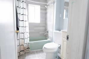 Bathroom with shower / bath combo with shower curtain, toilet, tile patterned floors, and vanity