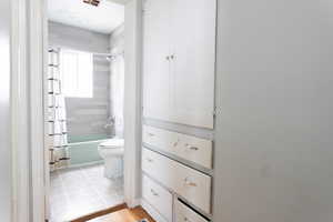Full bath with toilet, shower / tub combo, and wood finished floors