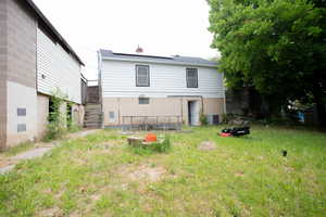Back of house with central AC, roof mounted solar panels, and stairway