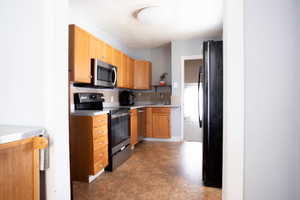 Kitchen featuring stainless steel appliances, a sink, light countertops, and tasteful backsplash