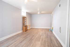 Basement with light wood-style floors, baseboards, and ceiling fan
