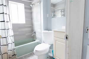 Bathroom with vanity, shower / bath combo, toilet, and tile patterned flooring