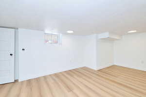 Basement featuring light floors, baseboards, and a textured ceiling