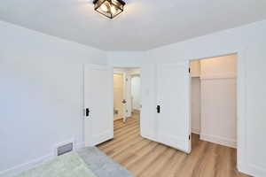 Unfurnished bedroom with light wood-style floors, baseboards, a closet, and a textured ceiling