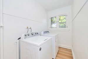 Laundry room featuring independent washer and dryer, light wood-type flooring, and baseboards