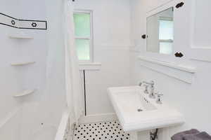 Full bath featuring a wainscoted wall, shower / bath combo, and a sink