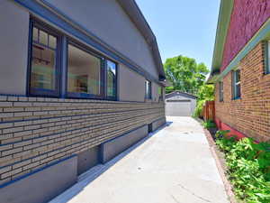 View of home's exterior with concrete driveway, a detached garage, brick siding, and an outbuilding