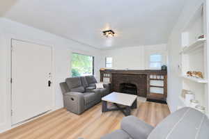 Living area featuring light wood-style floors, a fireplace, baseboards, and a textured ceiling