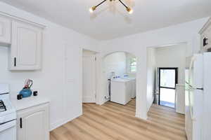 Washroom with separate washer and dryer, New LVP flooring, a textured ceiling, arched walkways, and a chandelier