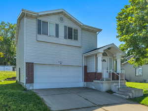 Traditional-style house with an attached garage, driveway, and brick siding