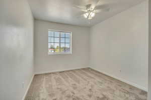 Spare room featuring carpet, baseboards, and ceiling fan