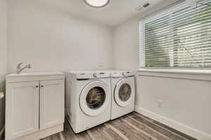 Washroom featuring independent washer and dryer, wood finished floors, baseboards, and cabinet space