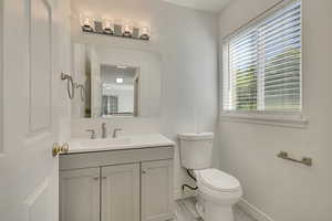 Half bath featuring baseboards, healthy amount of natural light, toilet, and vanity