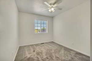 Carpeted spare room featuring ceiling fan, baseboards, and a textured ceiling