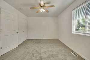 Spare room with light carpet, a ceiling fan, baseboards, and a smoke detector