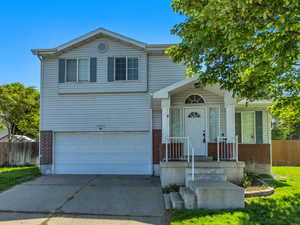 View of front facade with brick siding, a garage, and driveway