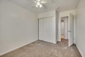 Unfurnished bedroom featuring carpet floors, a closet, baseboards, and ceiling fan