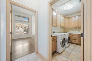 Laundry area with cabinet space, light tile patterned floors, washing machine and clothes dryer, and baseboards
