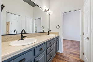 Full bathroom featuring wood finished floors, double vanity, and baseboards