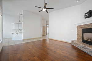 Unfurnished living room featuring light wood-style floors, ceiling fan, a fireplace, and baseboards
