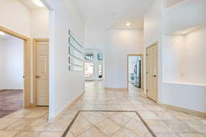 Hall featuring inlaid floor details, a towering ceiling, baseboards, and recessed lighting