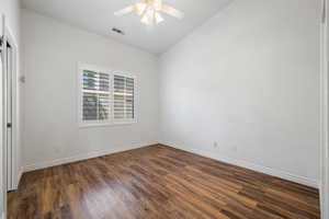 Spare room featuring dark wood-style floors, ceiling fan, vaulted ceiling, and baseboards