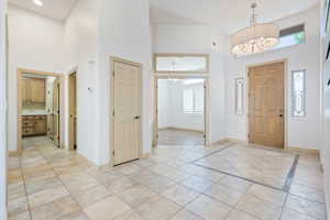 Entrance foyer featuring a towering ceiling, a chandelier, and baseboards