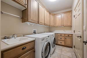 Laundry room featuring cabinet space, independent washer and dryer, and light tile patterned floors