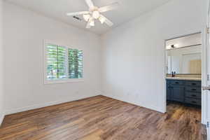 Unfurnished bedroom featuring dark wood-style floors, a sink, baseboards, and ensuite bathroom