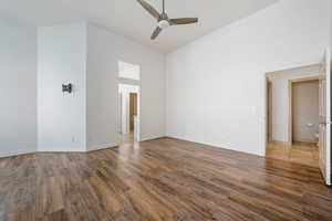 Spare room featuring high vaulted ceiling, a ceiling fan, wood finished floors, and baseboards