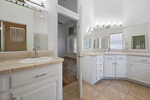 Bathroom with a shower stall, tile patterned flooring, and two vanities