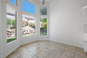 Empty room featuring a high ceiling, baseboards, and light tile patterned flooring