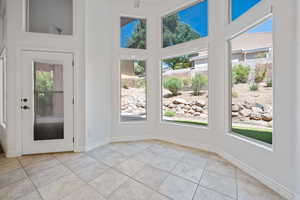 Empty room featuring light tile patterned floors, a towering ceiling, and baseboards