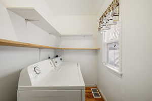 Laundry area featuring separate washer and dryer, dark wood-type flooring, and baseboards