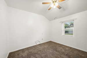 Bedroom 1 featuring carpet flooring, baseboards, vaulted ceiling, and a ceiling fan