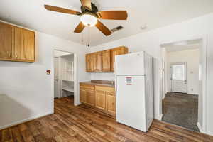 Kitchen featuring freestanding refrigerator, dark wood-type flooring, ceiling fan, and baseboards