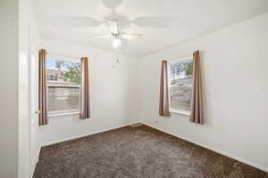 Bedroom 2 features plenty of natural light, dark colored carpet, a ceiling fan, and baseboards
