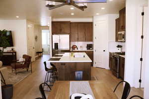 Kitchen with stainless steel appliances, light wood-style flooring, a sink, backsplash, and recessed lighting