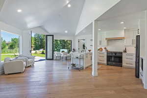 Living area with light wood-type flooring, vaulted ceiling, and recessed lighting