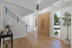 Entryway with lofted ceiling, light wood-type flooring, stairs, and baseboards