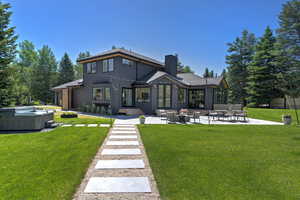 Back of property featuring a chimney, a patio area, and a lawn