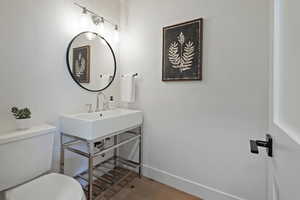 Bathroom with toilet, wood finished floors, baseboards, and vanity