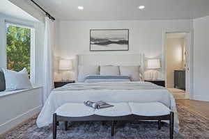 Bedroom with baseboards, wood finished floors, recessed lighting, and ensuite bath