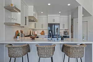 Kitchen featuring built in fridge, a peninsula, light countertops, recessed lighting, and white cabinets