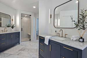 Full bath with marble finish flooring, recessed lighting, a stall shower, two vanities, and baseboards